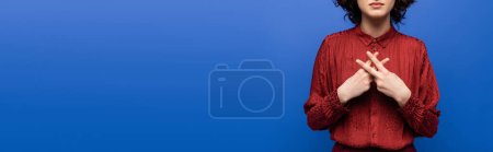 Photo for Partial view of teacher in red blouse gesturing on sign language isolated on blue, banner - Royalty Free Image