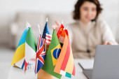 selective focus of various international flags near blurred laptop and language teacher having online lesson at home Stickers #645933140