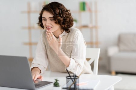 Photo for Positive teacher with curly hair showing thank you gesture during online lesson on laptop - Royalty Free Image