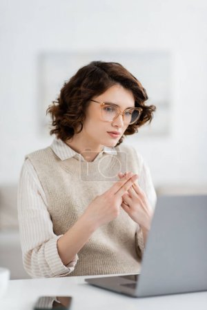 young teacher in glasses showing British two handed sign alphabet meaning letter f during online lesson  