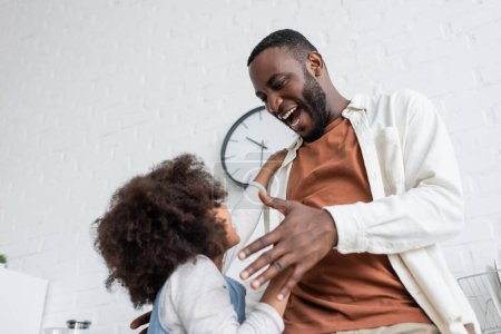 Niedrigwinkel-Ansicht von afrikanisch-amerikanischen Mann streckt die Hand in Richtung lockige Tochter, bevor sie einander umarmen 