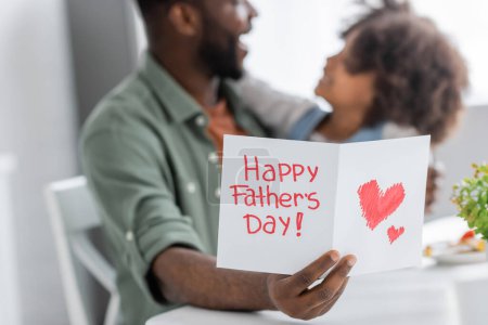Photo for African american man holding greeting card with happy fathers day lettering near curly daughter on blurred background - Royalty Free Image