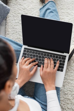 Foto de Vista superior de la mujer afroamericana escribiendo en el teclado del ordenador portátil mientras estudia desde casa - Imagen libre de derechos