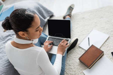 Foto de Vista superior de la mujer afroamericana utilizando el ordenador portátil con pantalla en blanco mientras estudia desde casa - Imagen libre de derechos