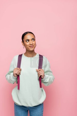 Hübsche afrikanisch-amerikanische Studentin mit Rucksack und Blick weg isoliert auf rosa 