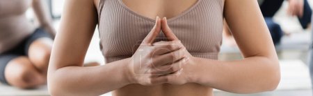 Cropped view of woman in top meditating in yoga class, banner 