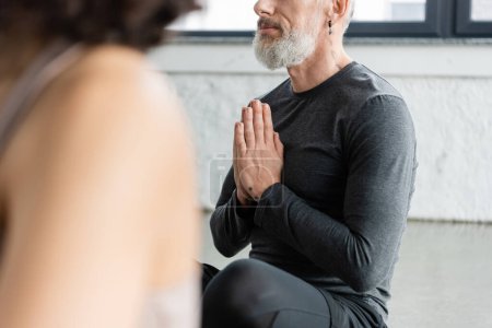 Vue recadrée de l'homme d'âge moyen pratiquant le mudra anjali en classe de yoga 