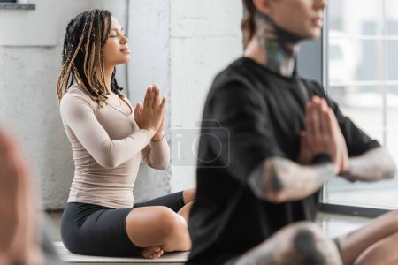 Jeune femme afro-américaine faisant anjali mudra dans un groupe de yoga 