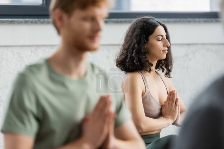 Middle eastern woman practicing anjali mudra in yoga group 