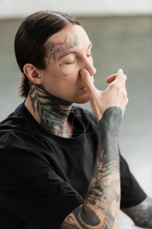 Foto de Hombre tatuado practicando respiración nasal y meditación en clase de yoga - Imagen libre de derechos