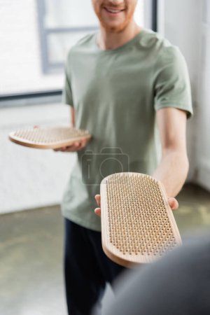 Photo for Cropped view of blurred smiling man holding sadhu board in yoga class - Royalty Free Image