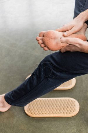 Foto de Vista parcial del hombre mostrando los pies desnudos después de la práctica de pie clavo en el estudio de yoga - Imagen libre de derechos