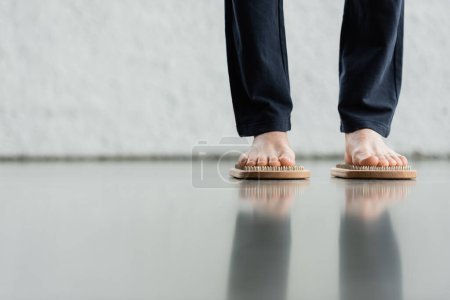 Téléchargez les photos : Vue recadrée de l'homme en pantalon debout sur la planche à ongles sadhu dans le studio de yoga - en image libre de droit