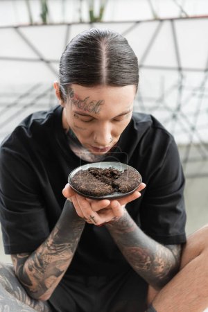 young man with tattoos smelling fermented tea leaves of puer in yoga studio 