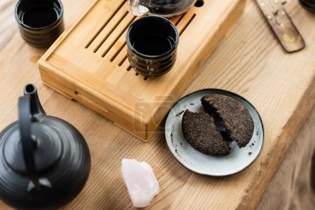 top view of compressed pu-erh tea on plate near Japanese teapot and cups in yoga studio 
