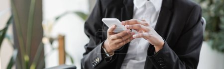 Photo for Cropped view of african american businesswoman in black blazer chatting on mobile phone in office, banner - Royalty Free Image