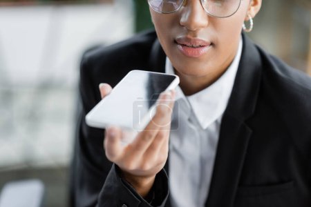 Photo for Cropped view of african american businesswoman sending voice message on mobile phone in office - Royalty Free Image
