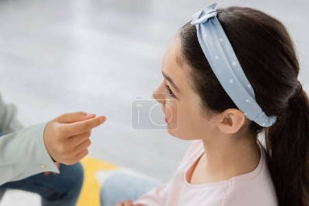 Preteen kid talking near speech therapist during correction lesson in consulting room  