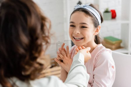 Blurred speech therapist working with cheerful pupil in consulting room