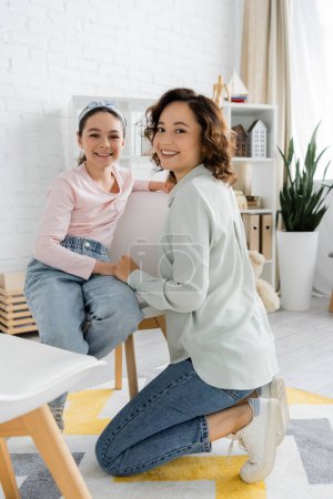 Smiling speech therapist and pupil looking at camera in consulting room 