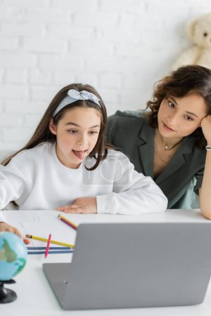 Kind streckt während Logopädie-Online-Unterricht bei Eltern zu Hause die Zunge heraus 