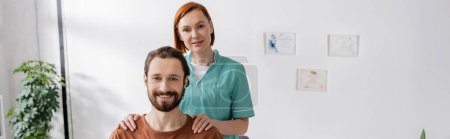 joyful physiotherapist and bearded man smiling at camera in rehabilitation center, banner
