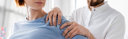 Photo for Partial view of rehabilitologist examining injured shoulder of patient in consulting room, banner - Royalty Free Image