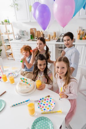 group of happy children blowing party horns during birthday celebration 