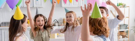 Téléchargez les photos : Enfants excités dans les casquettes de fête s'amuser pendant la célébration d'anniversaire à la maison, bannière - en image libre de droit