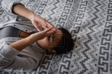 Blick aus der Vogelperspektive auf eine Frau mit Depressionen, die zu Hause im Bett liegt 
