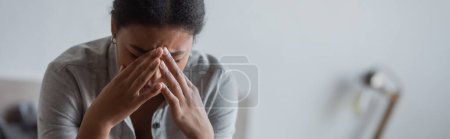 Junge multirassische Frau weint in verschwommenem Schlafzimmer zu Hause, Banner 