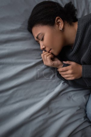 Photo for Top view of frustrated multiracial woman lying on bed at home - Royalty Free Image