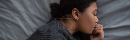 Photo for Side view of multiracial woman with depression lying on grey bedding, banner - Royalty Free Image