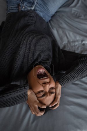 Téléchargez les photos : Vue du dessus de la femme multiraciale avec dépression hurlant tout en étant couché sur le lit - en image libre de droit