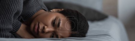 Foto de Mujer multirracial frustrada con depresión acostada en una cama borrosa en casa, pancarta - Imagen libre de derechos