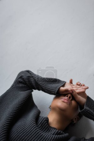 Téléchargez les photos : Vue à angle bas de la femme multiraciale avec dépression appuyée sur le mur à la maison - en image libre de droit