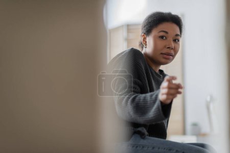 Téléchargez les photos : Femme multiraciale inquiète avec un problème psychologique pointant vers la caméra à la maison - en image libre de droit