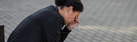 Téléchargez les photos : Vue latérale de la jeune femme multiraciale avec dépression regardant vers le bas sur la rue urbaine, bannière - en image libre de droit