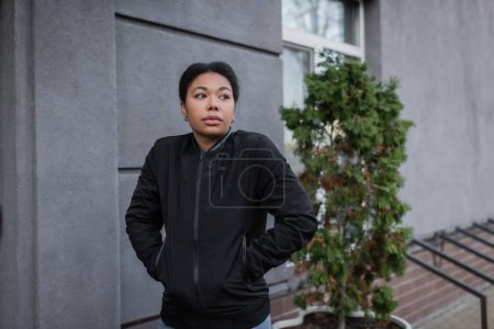Photo for Multiracial woman with mental problem standing near building on urban street - Royalty Free Image