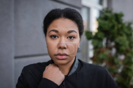 Portrait of multiracial woman with depression looking at camera on urban street 