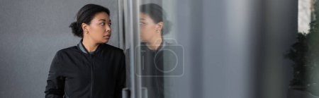 femme multiraciale avec problème mental regardant le verre sur la façade du bâtiment, bannière 