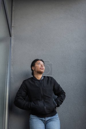 Téléchargez les photos : Femme multiraciale avec un problème mental debout près du mur du bâtiment à l'extérieur - en image libre de droit