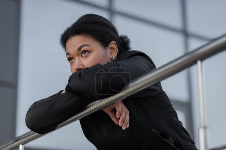 multiracial woman with mental crisis standing near railing on urban street 