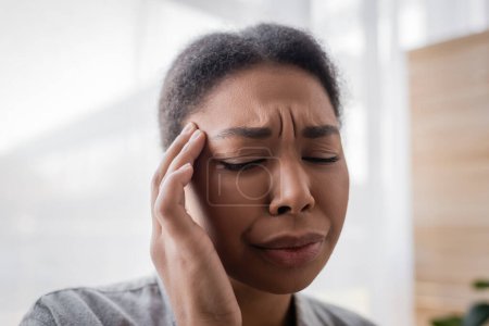 Mujer joven multirracial que sufre de dolor en la cabeza en casa 