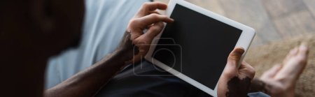 Téléchargez les photos : Vue recadrée de l'homme afro-américain avec vitiligo tenant tablette numérique avec écran blanc à la maison, bannière - en image libre de droit