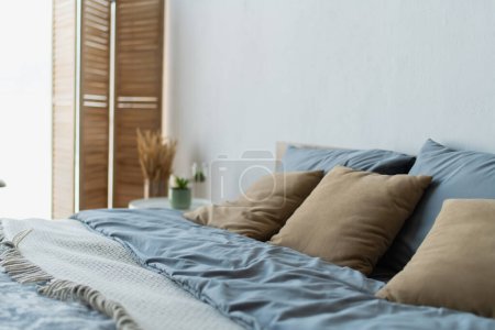 Almohadas en cama cómoda en dormitorio borroso 