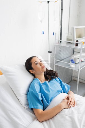 high angle view of sick and stressed asian woman lying on hospital bed and looking away