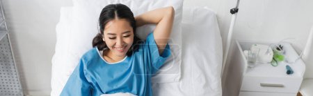 Foto de Joven asiático mujer en hospital bata sonriendo en cama, bandera - Imagen libre de derechos