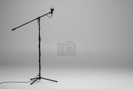 Photo for Black microphone with wire on metal stand on grey background with copy space - Royalty Free Image