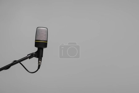 Mikrofon mit Draht auf schwarzem Metallständer isoliert auf grau mit Kopierraum, Studiofoto 